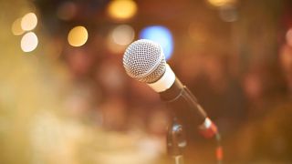 Microphone in foreground closeup, blurred lights in background.