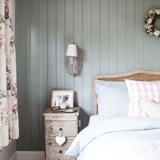 Pastel bedroom with wall panelling and blue sheets on bed