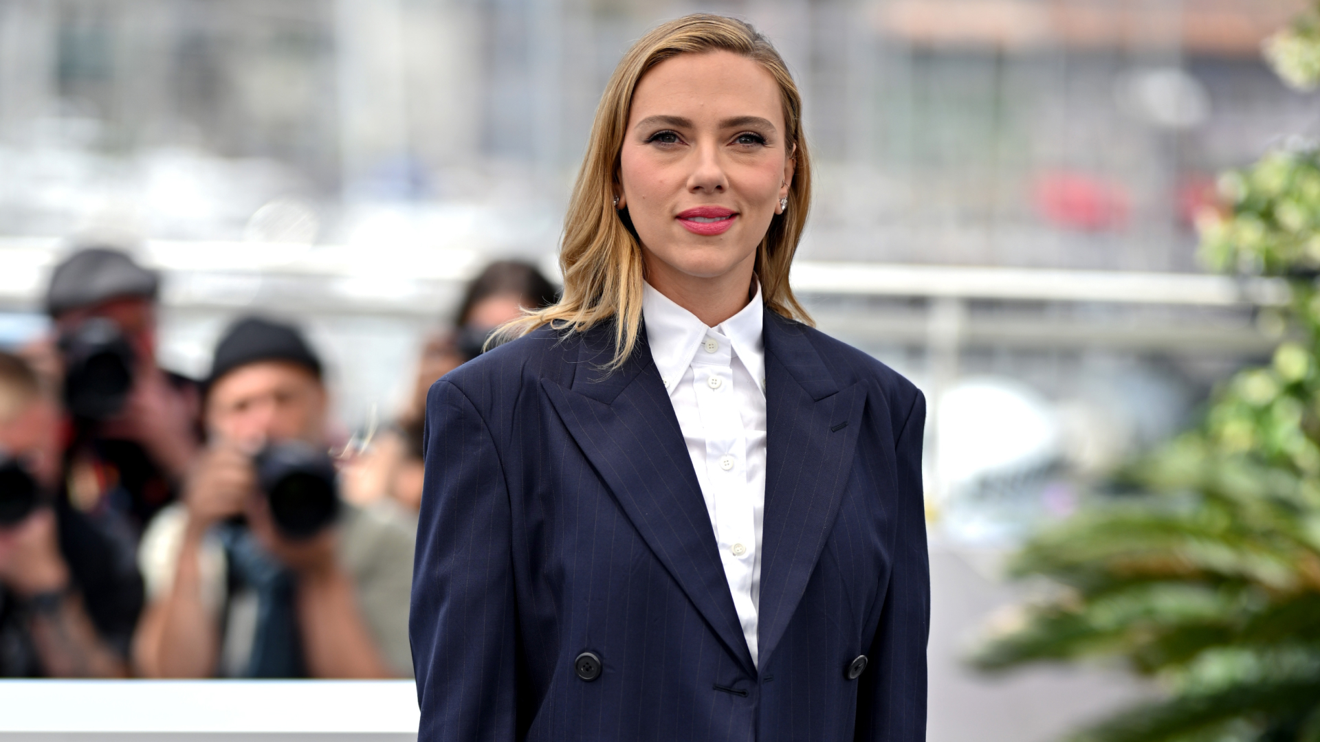 Scarlett Johansson wearing a blazer and button-up top. She&#039;s wearing her hair down with a side part. 