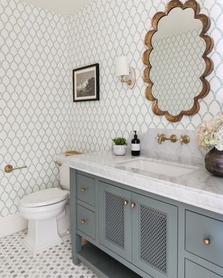powder room with blue gray washstand, trellis wallpaper and brass mirror