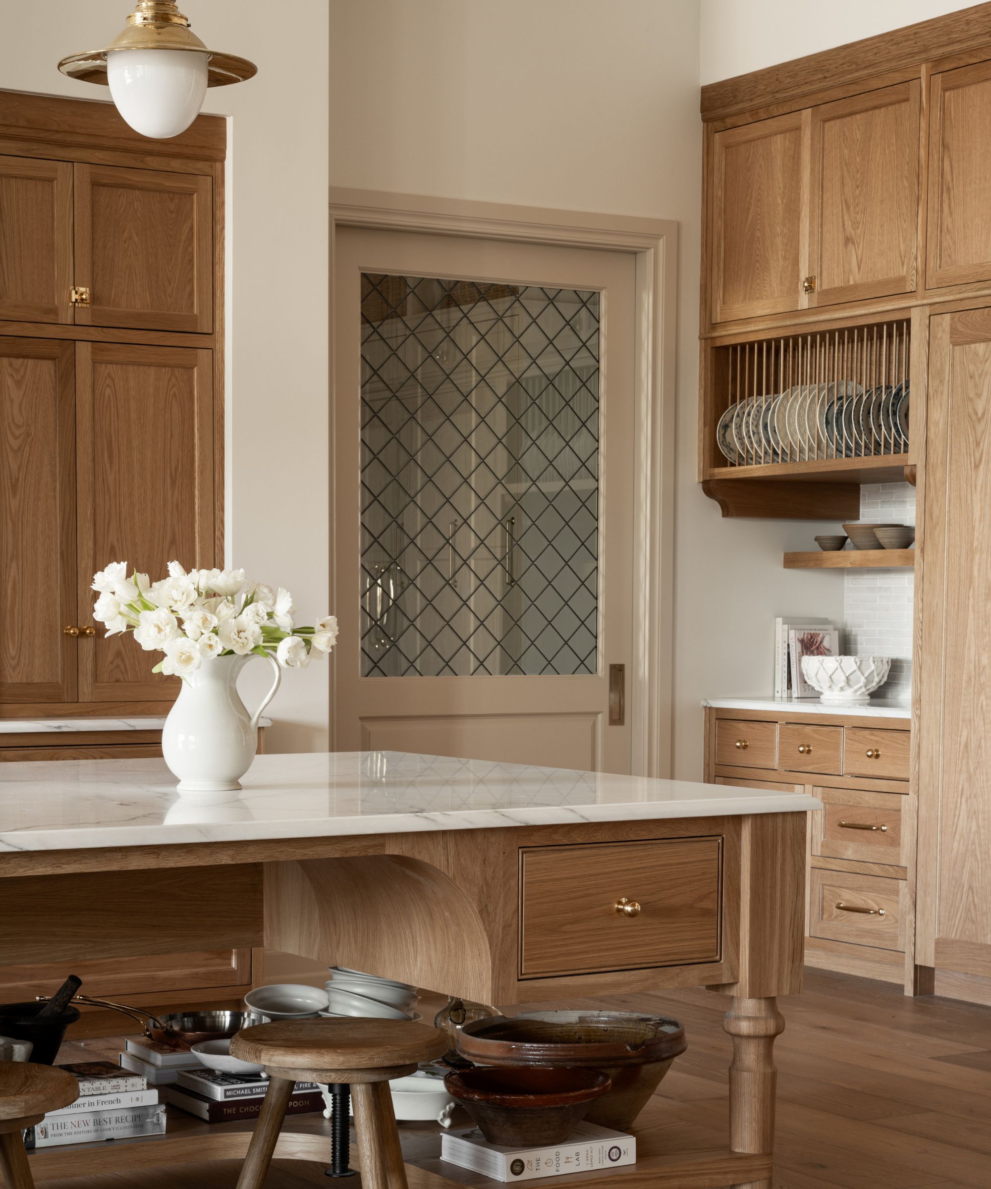 The corner of a large wooden kitchen featuring a bank of drawers, countertops space, and a shelf and plate rack above
