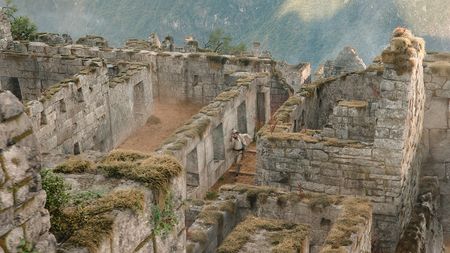 Making Paddington in Peru's ruined city; An elevated, high-angle view showcases a section of a stone ruin, likely a historical site, with a person navigating the crumbling structures.