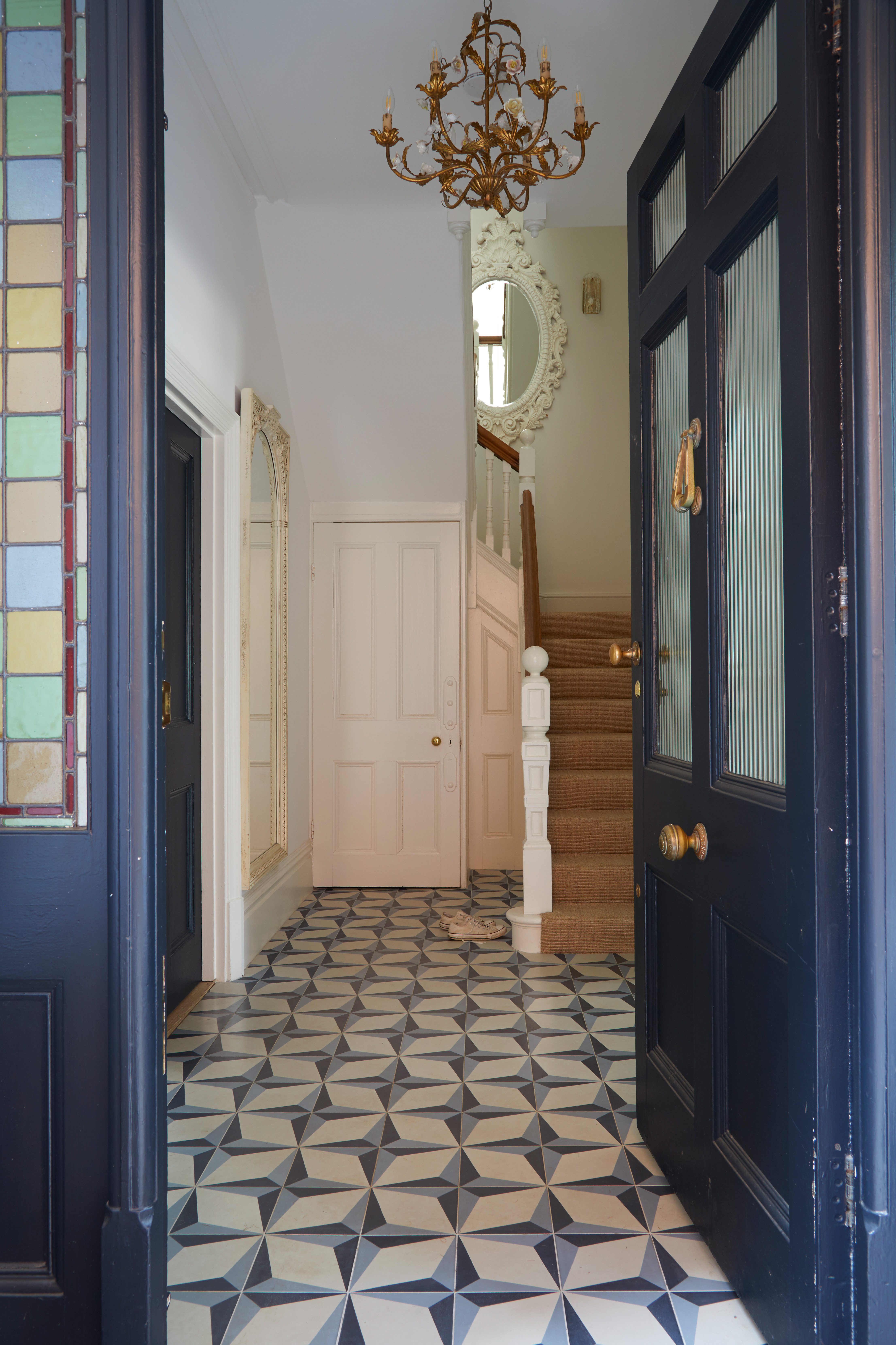 Hallway with patterned tiles blue door and mirrors