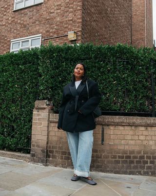 woman wearing cuffed denim outfit with black blazer and studded flats