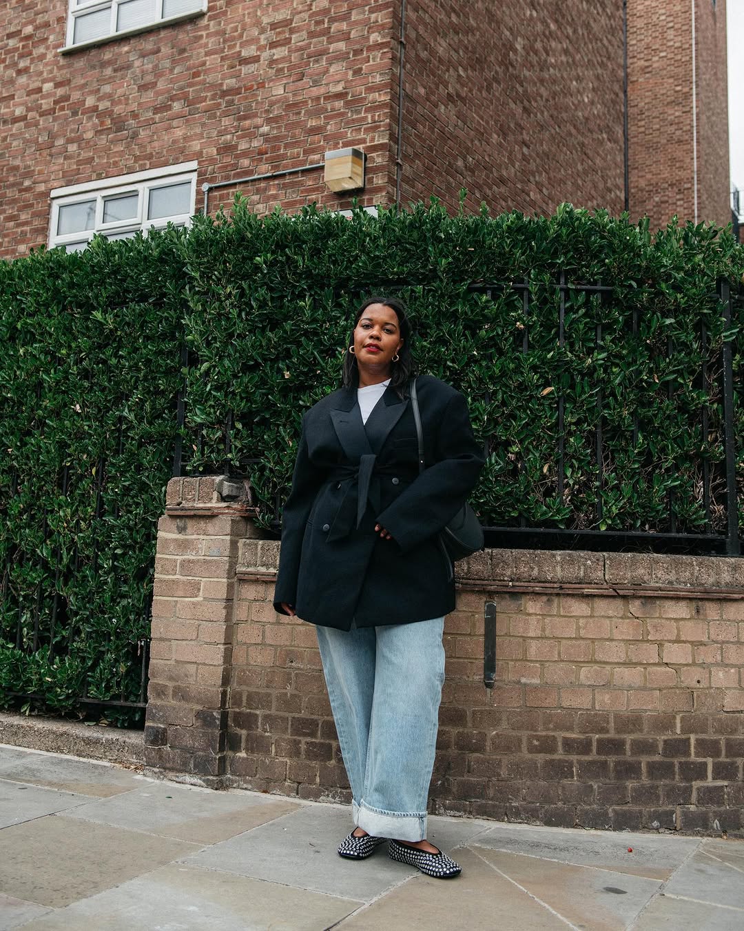 Mulher usando roupa jeans de algema com blazer preto e apartamentos cravejados