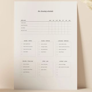 A white A4 cleaning checklist leaning against a peach pink background