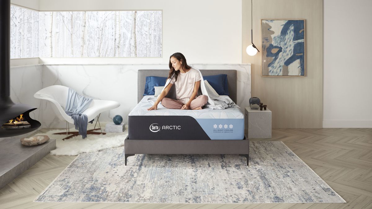 A woman with dark hair sits on the new Serta Arctic Mattress for cooler sleep