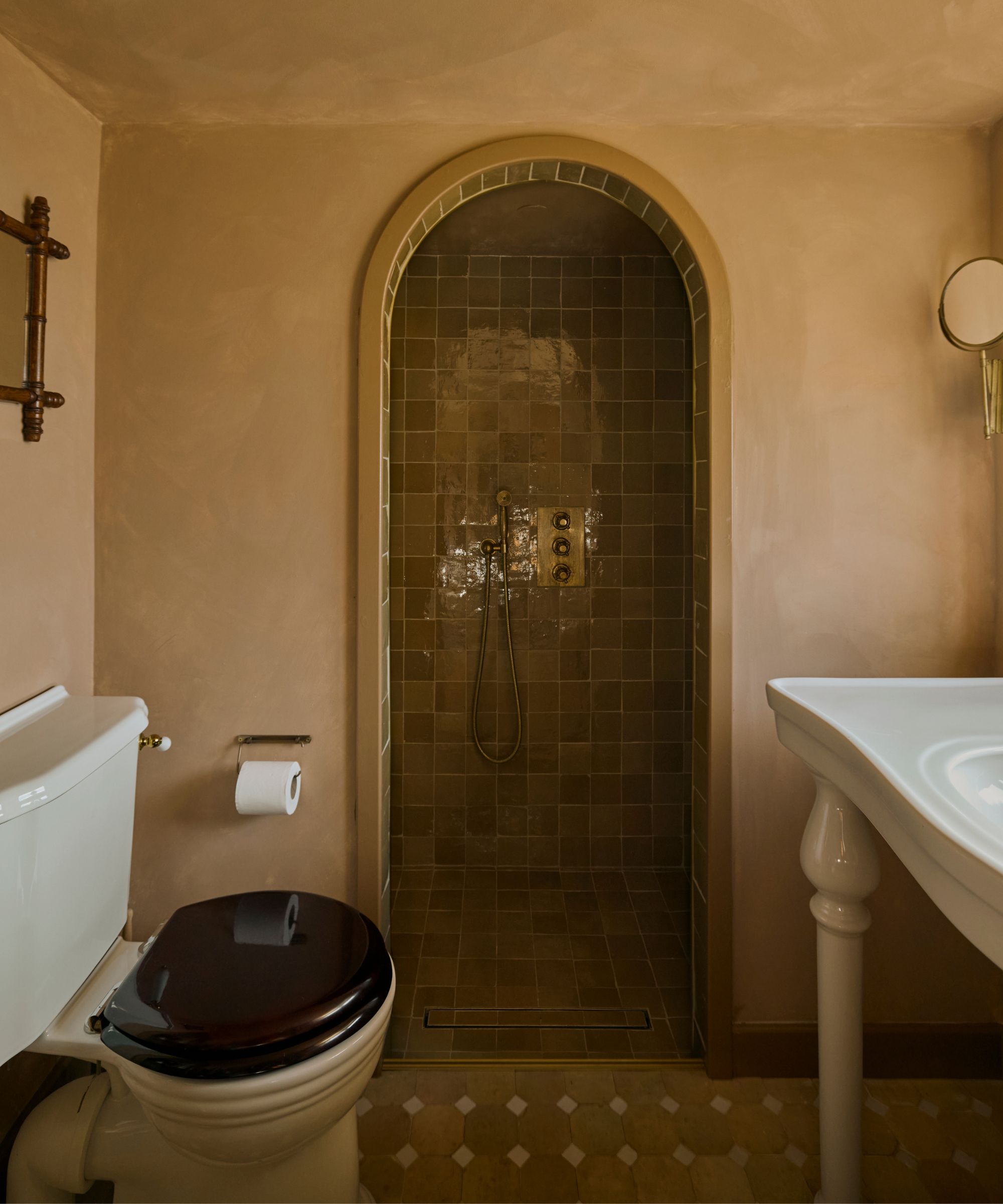 A tiny home bathroom with limewash walls, a white freestanding sink, and a shower nook lined with green square tiles