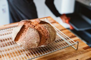 Freshly baked sourdough bread cooling on wire rack over wooden countertop