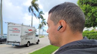 The reviewer wearing the Edifier NeoBuds Pro outside by a road on a which a truck is driving