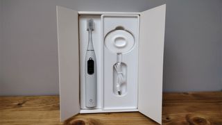 Image shows the electric toothbrush in its open packaging, along with the accessories that come with it.