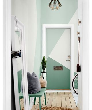 Mint green hallway with mirror, jute rug, pendant light and bicycle