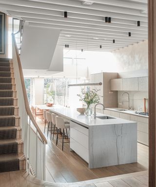 Modern and neutral Chelsea townhouse with kitchen island lighting as well as spotlights across the kitchen