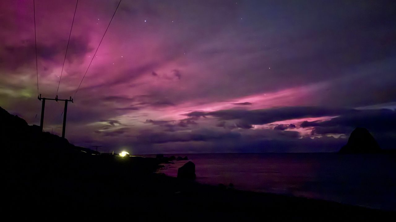 a pink and purple sky with hints of red and faint green on the left. The northern lights make the scene look like a dreamscape.