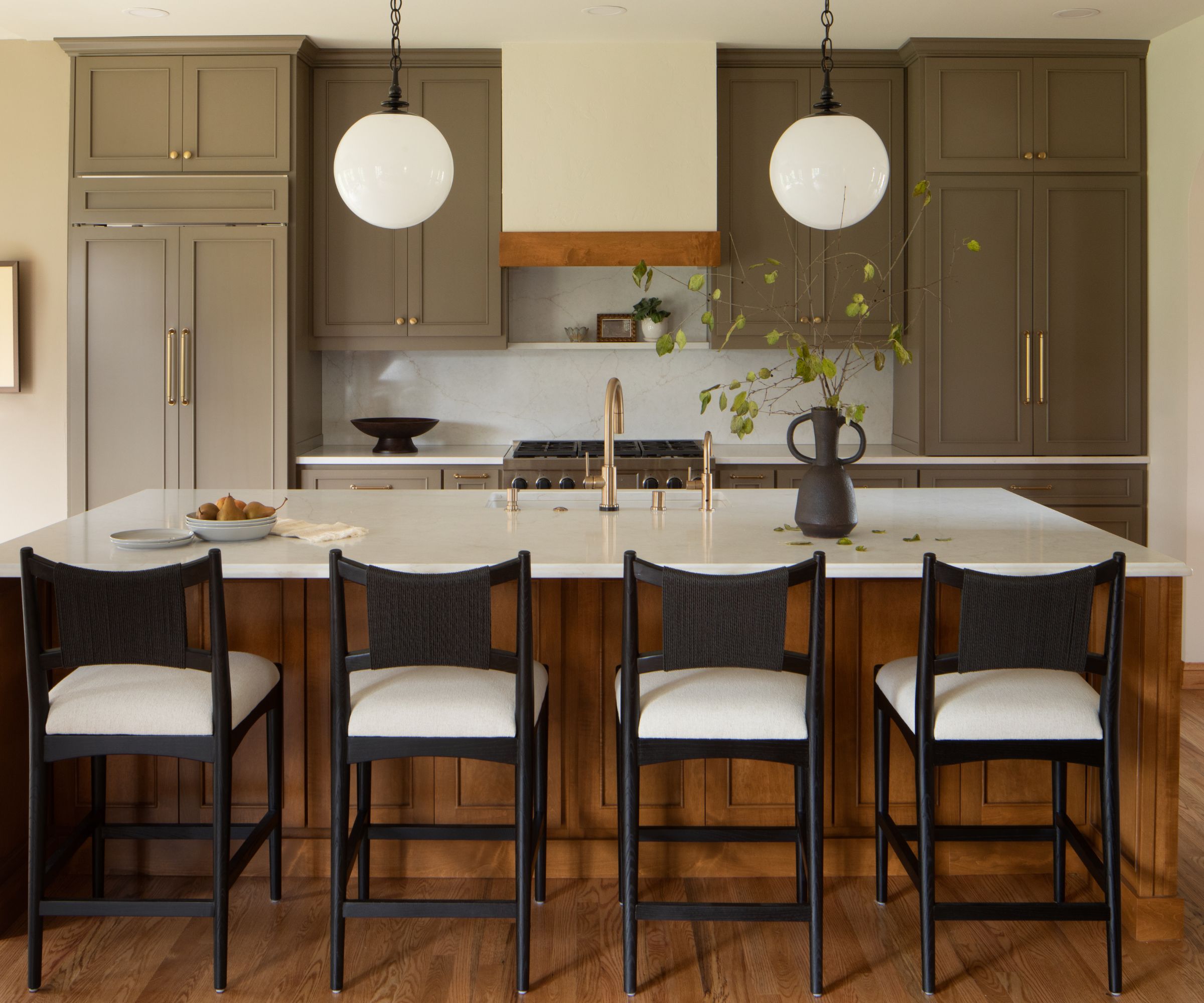 A large kitchen with muddy green cabinets and a wooden island