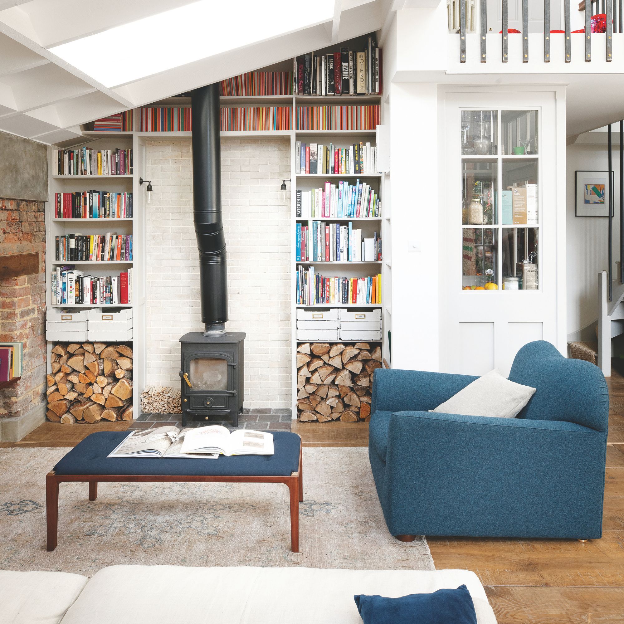 Living room with high ceilings and a log burner, surrounded by books