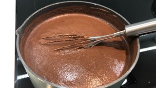 A whisk in hot chocolate in a saucepan