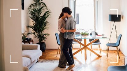Couple dancing romantically in their living room, next to dining room table that could work for the butterfly sex position
