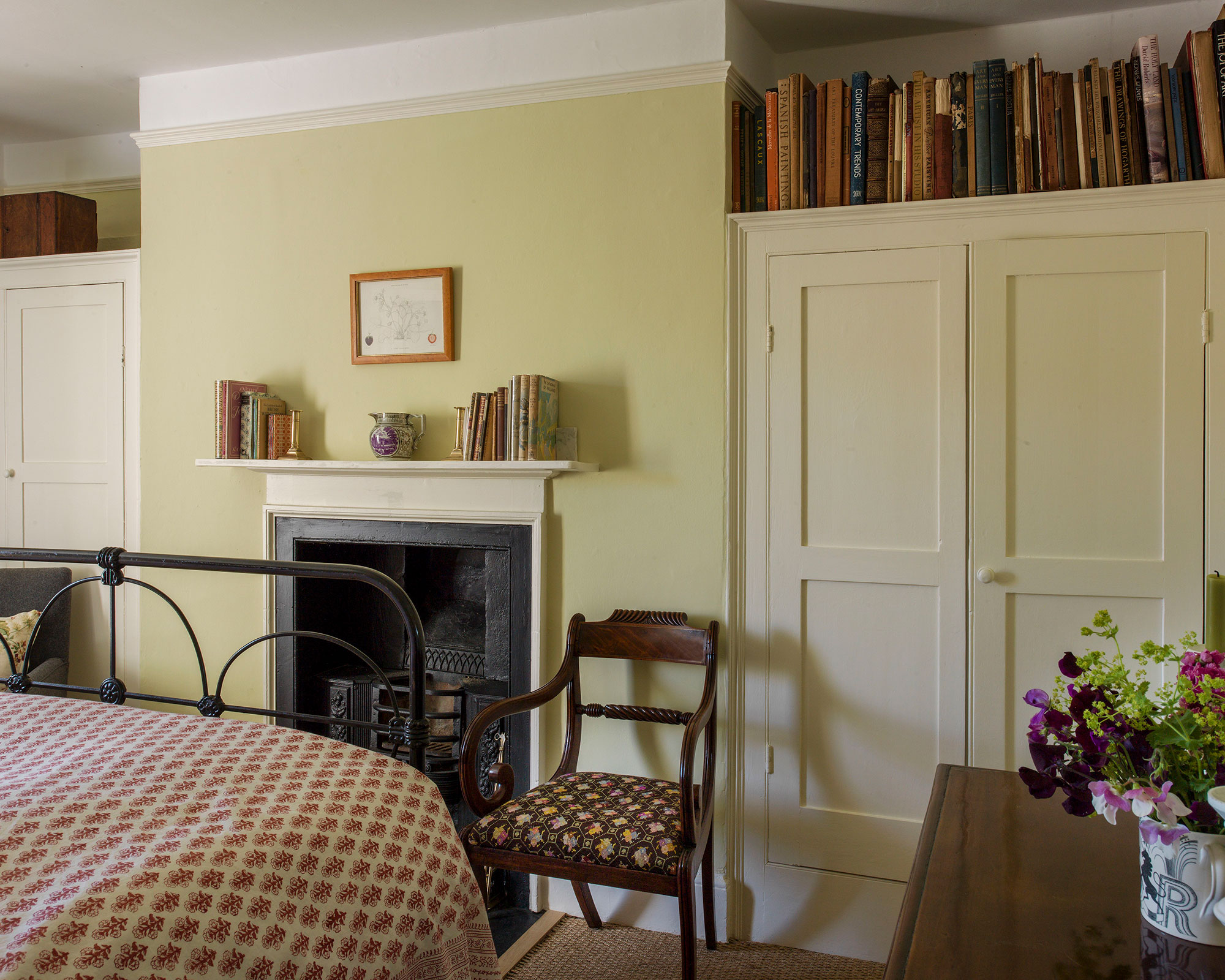 A neutral Ben Pentreath bedroom with small bedroom layout ideas including built-in alcove storage and mantelpiece shelving.