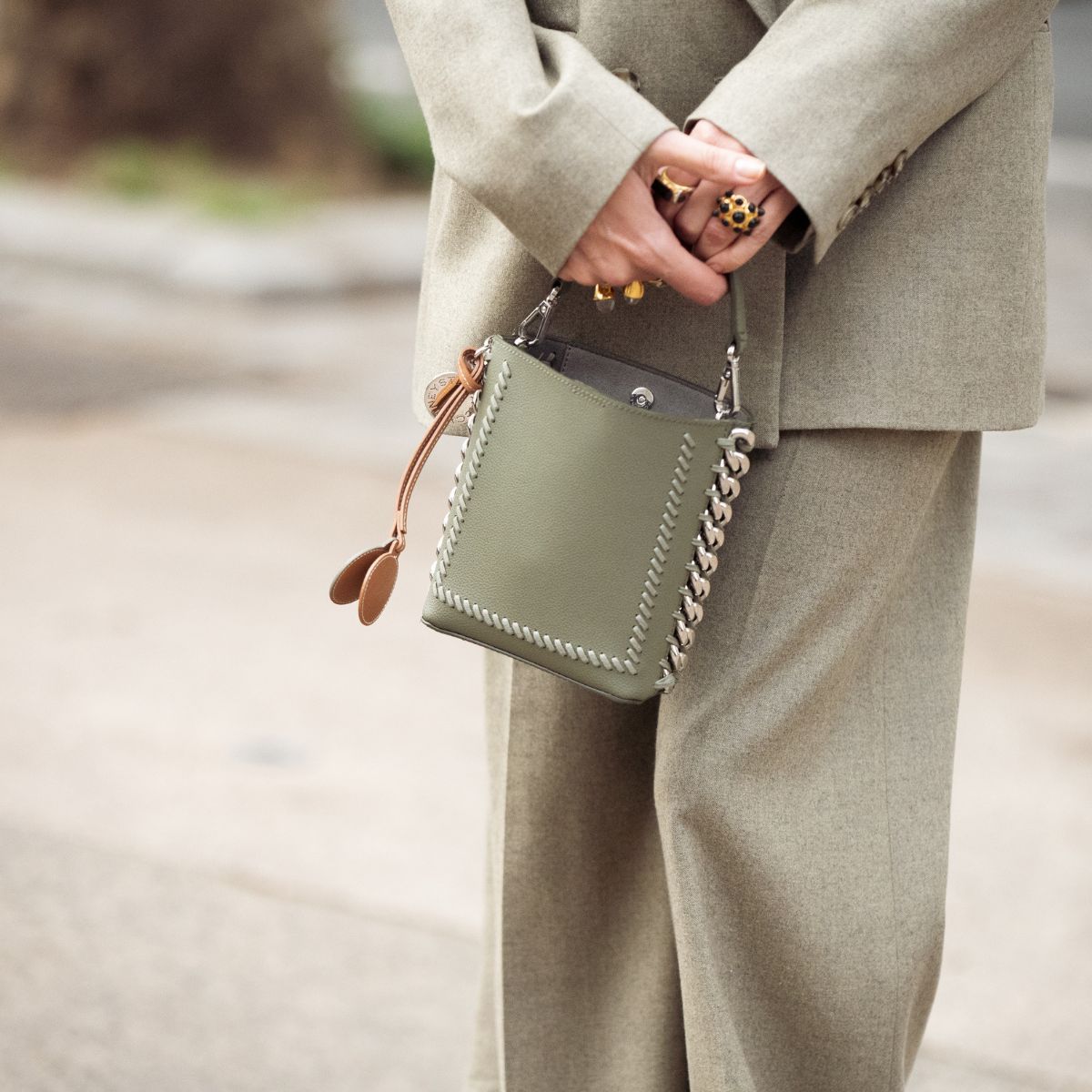A woman in a green suit holding a green designer handbag