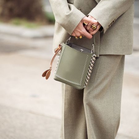 A woman in a green suit holding a green designer handbag