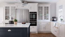 white kitchen with blue island and large stainless steel fridge