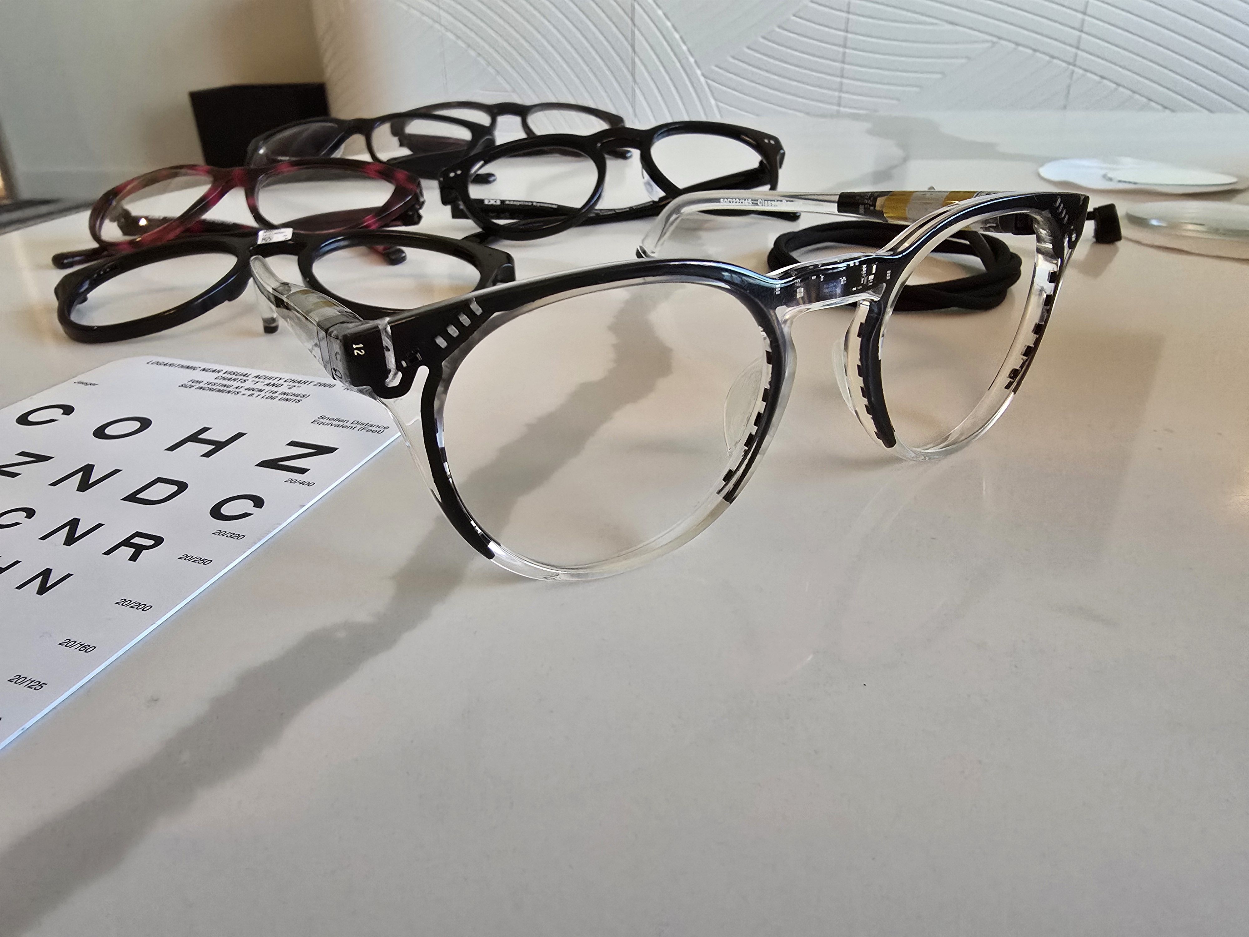 A prototype version of IXI's smart glasses is unpainted to reveal the components hidden within the frame. At back, the finished product.