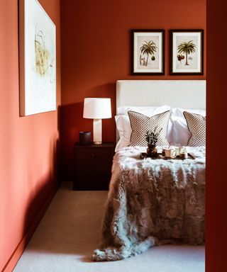 An orange-red bedroom with white headboard and cream bedding