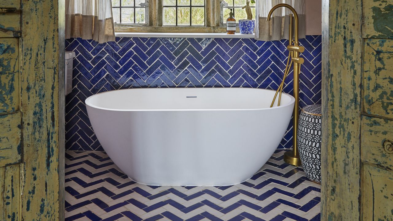 Bathroom with chevron tiled flooring and white bath