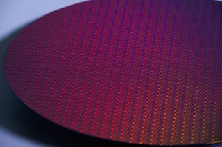 A close-up stylized photo of a silicon wafer, showing many small processor dies