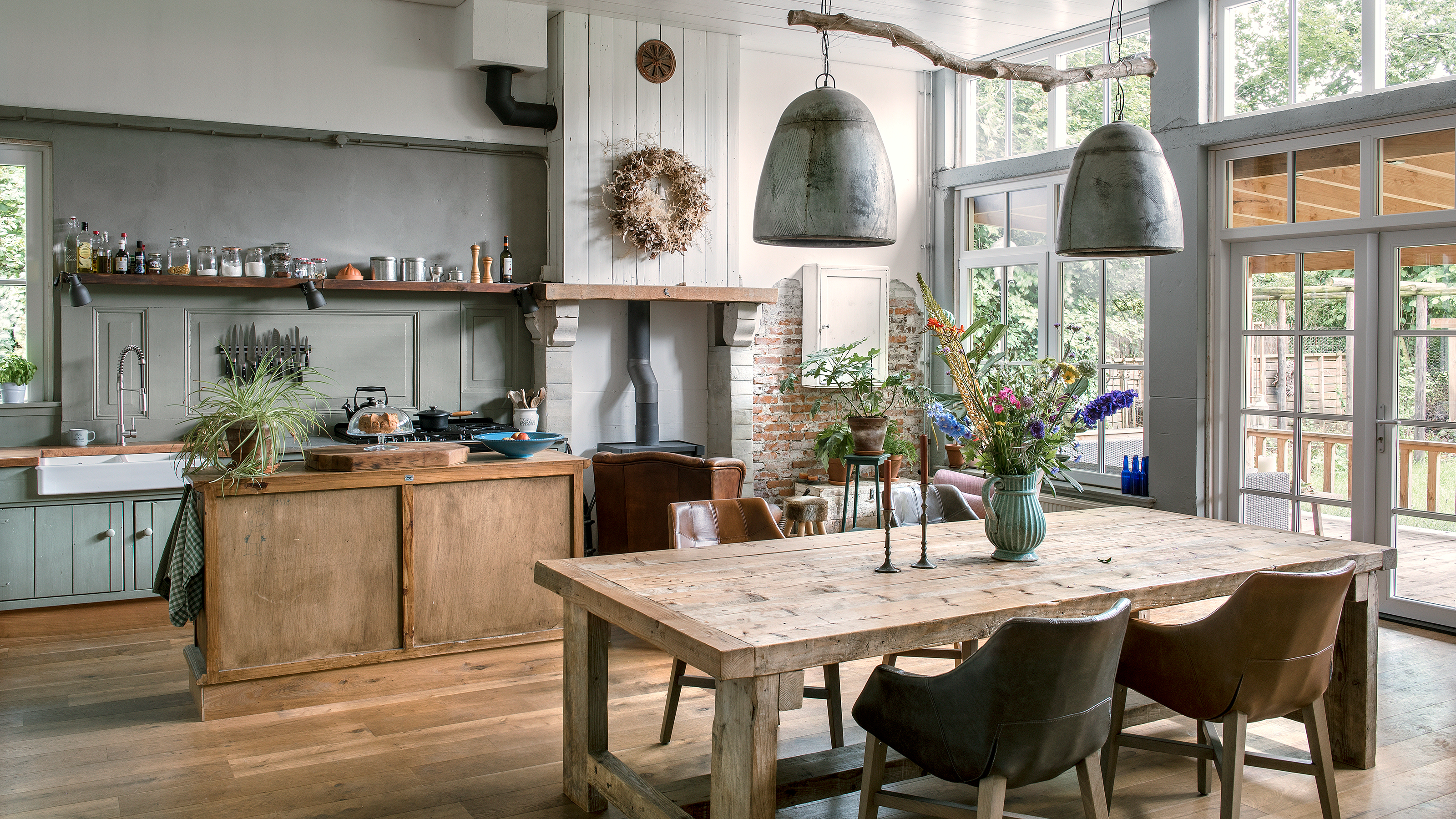 open plan kitchen diner in a converted school with large industrial pendant lights and wall of windows