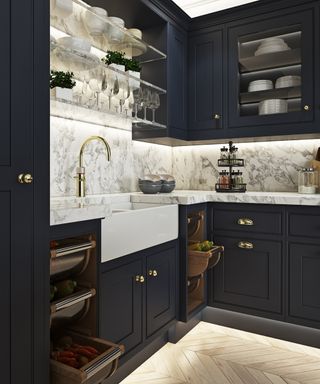 A dark blue kitchen with gold faucet and shelf lighting ideas.