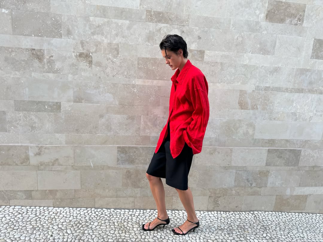 Sobalera wears a red shirt, black shorts and blacks sandals