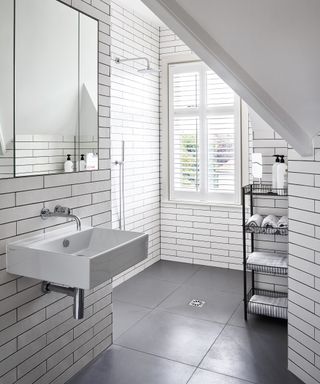 A small loft wet room with white metro tiled walls and black flooring.