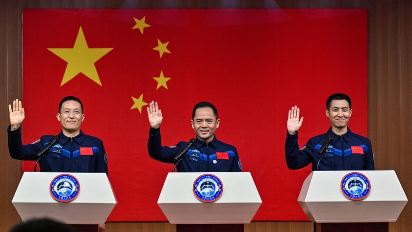 Three men wearing uniforms stand behind three podiums with a Chinese flag behind them