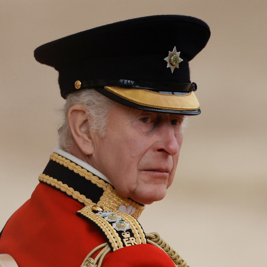 King Charles wears red military uniform and a black hat at Trooping the Colour