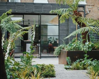 a backyard terrace area with corten steel planters and crittal patio doors