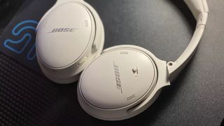 The Bose QuietComfort 45 over-ear headphones in white on a dark surface