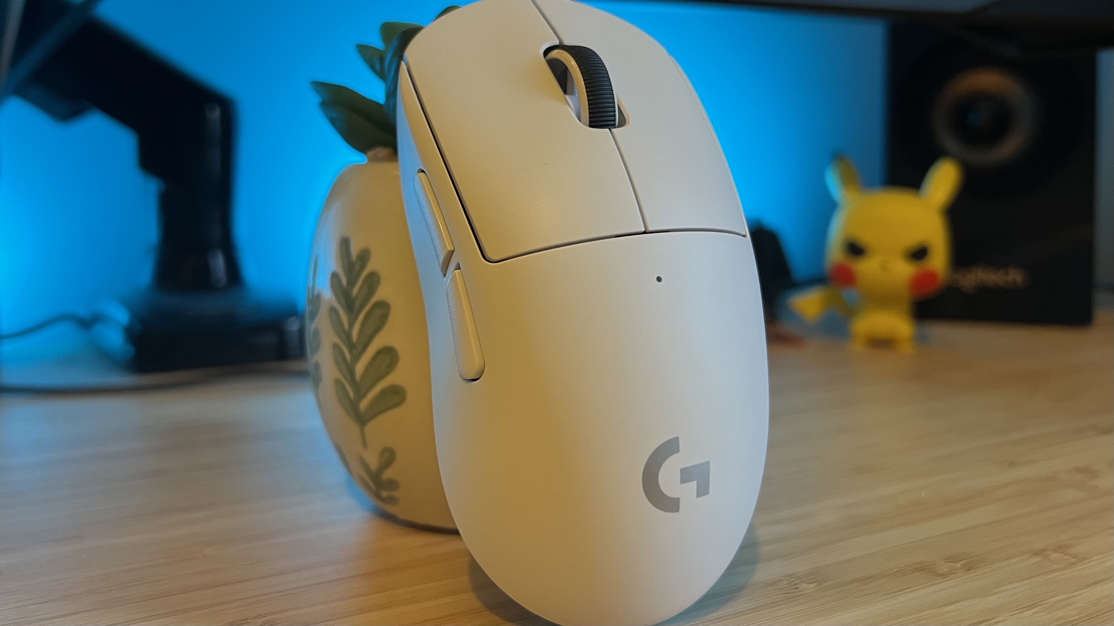 Logitech G Pro X Superlight 2c gaming mouse on a wooden desk with blue backlighting