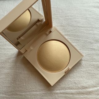 An open Laura Mercier Real Flawless Pressed Powder set against a white linen background