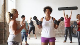 woman lifting dumbbells beside trainer in fitness class