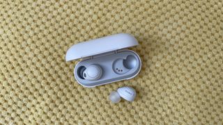 Sony WF-C700N wireless earbuds on a yellow pillow