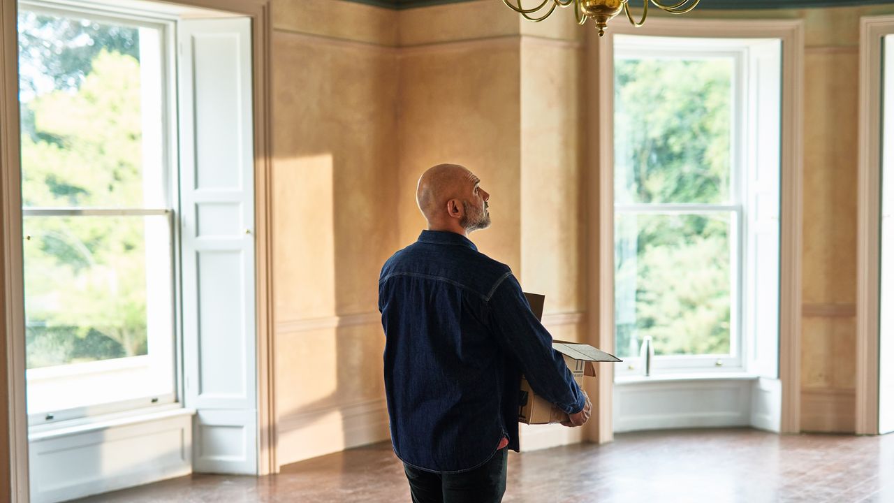 A man carries a box into his new home.