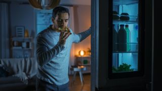 A photo of a man snacking in the fridge