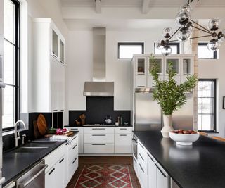 kitchen with black worktops white cabinets and white walls with contemporary pendant light above counter