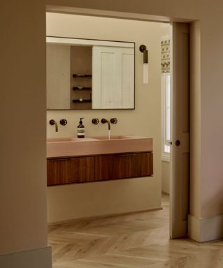 White bathroom with a wood vanity topped with a pink stone countertop