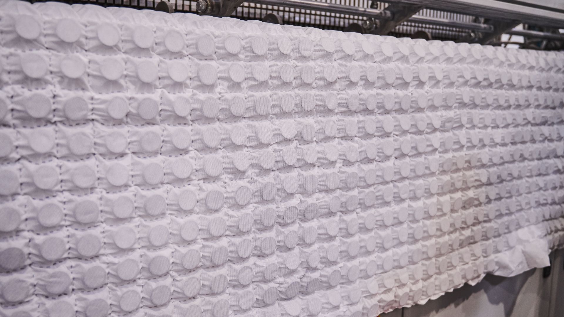 Fabric-encased microcoils being manufactured in a large factory.