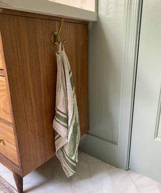 Wooden bathroom cabinet with brass towel hook installed