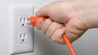 A man unplugging a power cable from a wall outlet