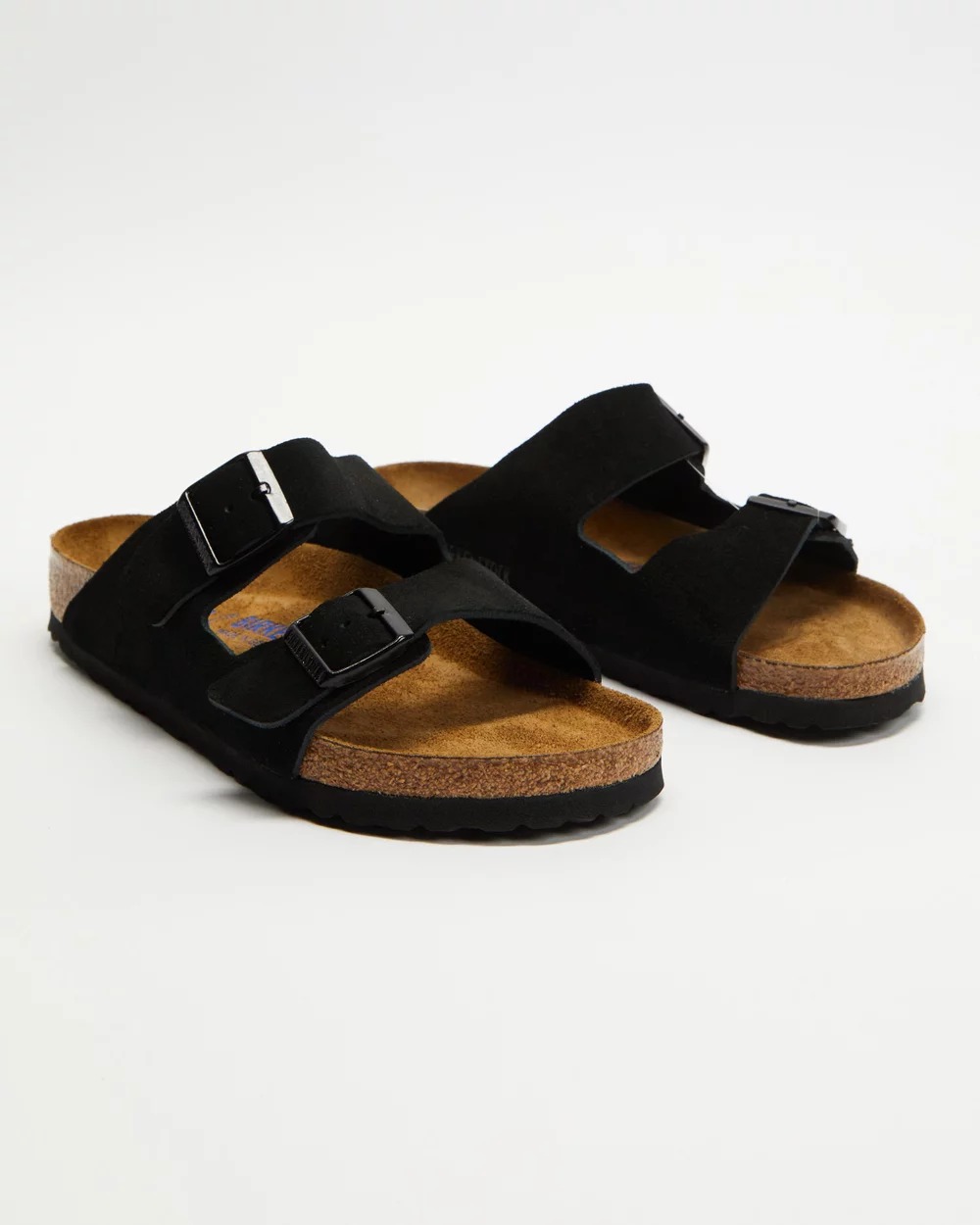 A pair of Birkenstock Arizona sandals with black suede straps and a dark cork coloured footbet